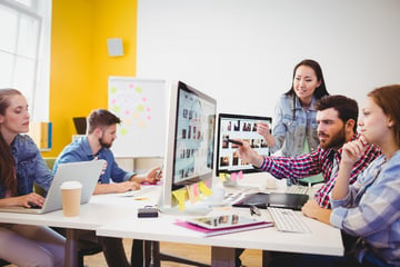 Businessman showing computer screen to coworkers in creative office